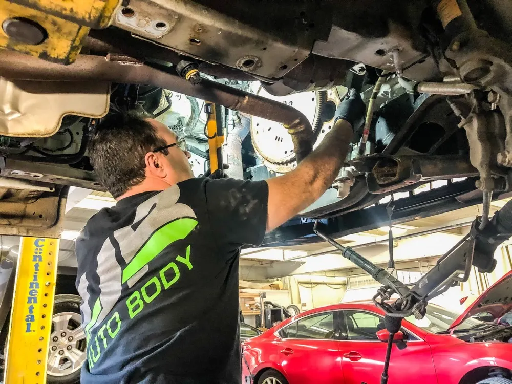 WR Auto Body mechanic working under a lifted vehicle in the shop